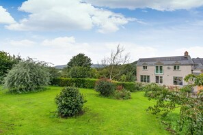 A house with a well-maintained lawn, a variety of shrubs, and a clear sky. - 3 Bed in Grizebeck (oc-b45345) (Kirkby Ireleth)