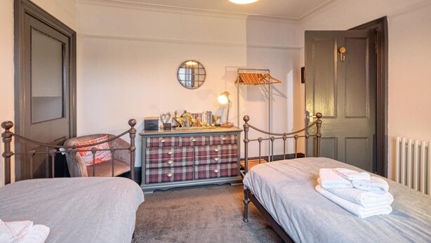 Ein Schlafzimmer mit zwei Betten, einem Schminktisch, einem Spiegel und einer Hängelampe.