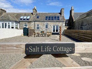 A stone cottage with a sign reading 'Salt Life Cottage' in front. - 3 Bed in Port William (oc-s45456) (Port William)