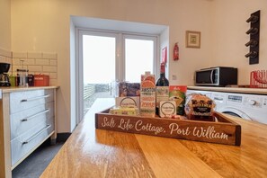 A kitchen with a wooden countertop, a coffee machine, a microwave, and a window with a view of the outside. - 3 Bed in Port William (oc-s45456) (Port William)