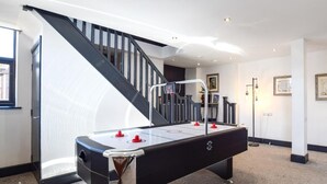 Ein Billardtisch in einem Raum mit einer Treppe und einem gerahmten Bild an der Wand.