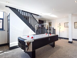 Ein Billardtisch in einem Raum mit einer Treppe und einem gerahmten Bild an der Wand.