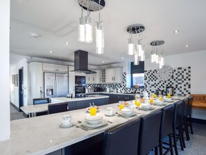A modern kitchen with a central island, pendant lighting, and a checkered backsplash. - 5 Bed in Driffield (oc-80371) (Burton Fleming)