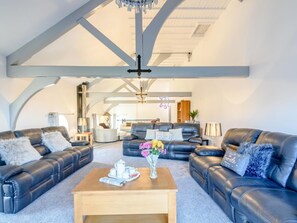 Ein geräumiges Wohnzimmer mit Ledersofas, einem Holztisch und einer Kandelaber.