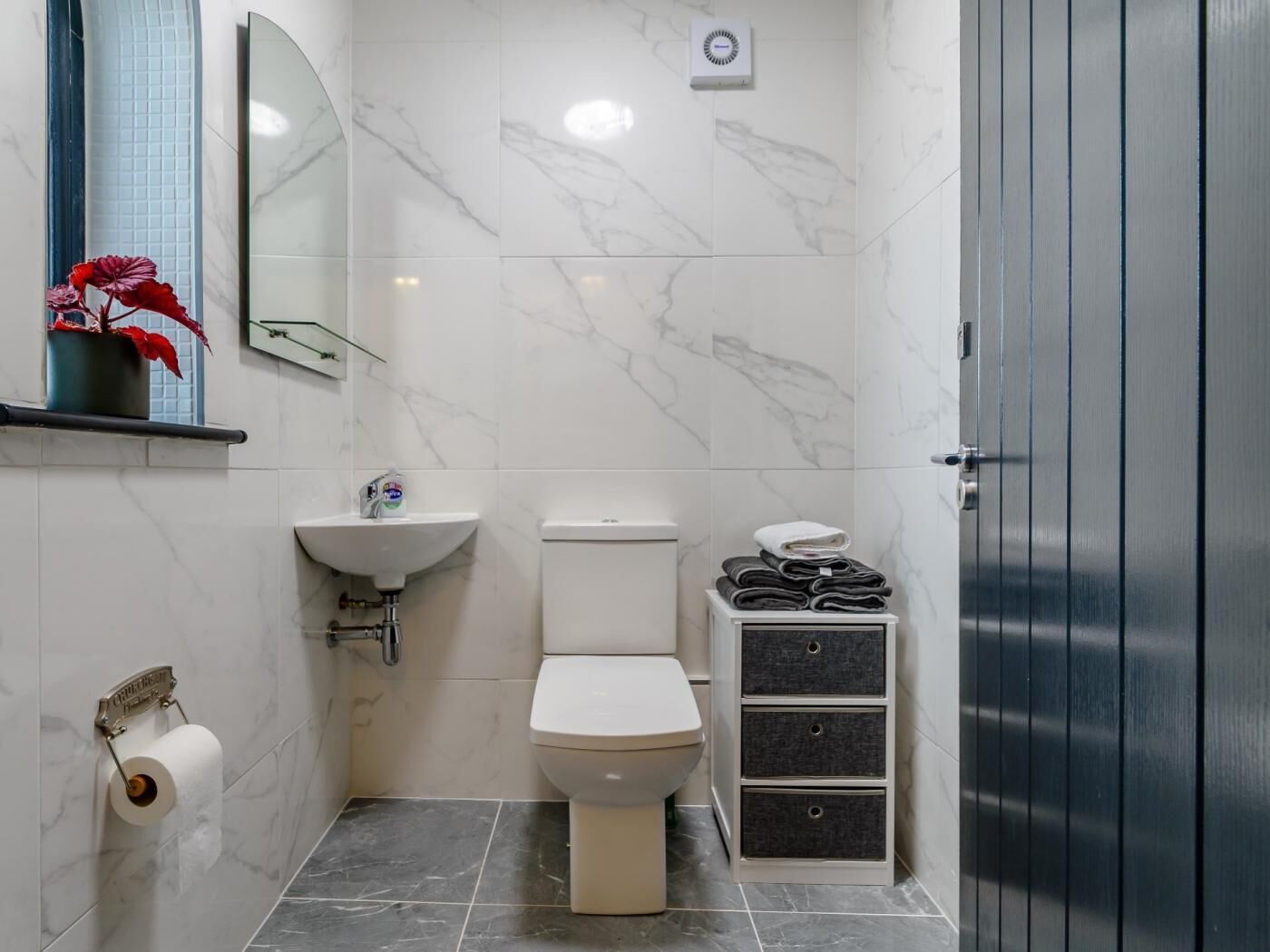 Un baño con inodoro, lavabo y toallero con toallas dobladas.