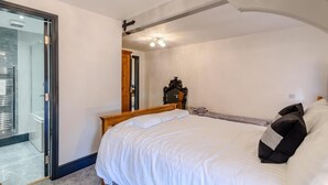 Ein Schlafzimmer mit einem Bett, einem Holzkopfende, einem Spiegel und einer Tür zu einem Badezimmer.