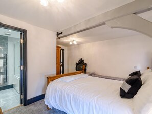 Ein Schlafzimmer mit einem Bett, einem Holzkopfende, einem Spiegel und einer Tür zu einem Badezimmer.