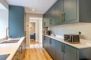 Eine moderne Küche mit eingebautem Toaster, einer Spüle aus Edelstahl und Holzböden.