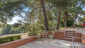 Une terrasse avec un mur en briques, un banc en bois et une table avec des chaises.