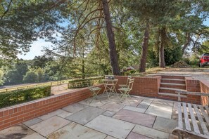 Eine Terrasse mit einer Ziegelmauer, einer hölzernen Bank und einem Tisch mit Stühlen.