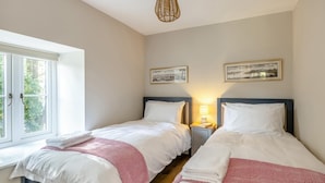 Une chambre d’hôtel avec deux lits, une fenêtre et une lampe fixée au mur.