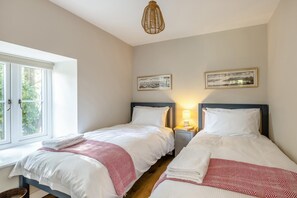 Ein Hotelzimmer mit zwei Betten, einem Fenster und einer Wandlampe.