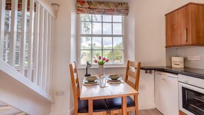 A kitchen with a dining table, chairs, a window with a view, and a cabinet. - 1 Bed in Ambleside (oc-a45864) (Ambleside)