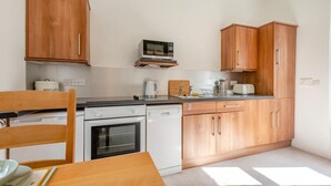 A compact kitchen with wooden cabinets, a microwave, a toaster, and a dishwasher. - 1 Bed in Ambleside (oc-a45864) (Ambleside)