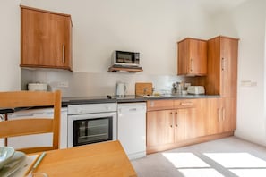 Eine kleine Küche mit Holzschränken, einer Mikrowelle, einem Toaster und einem Geschirrspüler.