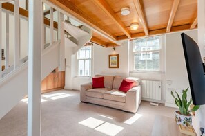 A modern interior with a staircase, a beige sofa with red cushions, and a potted plant. - 1 Bed in Ambleside (oc-a45864) (Ambleside)