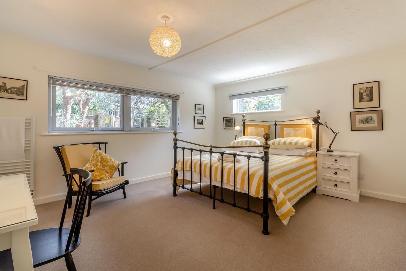 A bedroom with a bed, a chair, a nightstand, and a window.