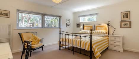 Une chambre à coucher avec un lit, une chaise, une table de chevet et une fenêtre.