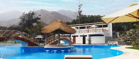 A swimming pool with a bridge, lounge chairs, and a building with a sign reading 'Los Andes'.