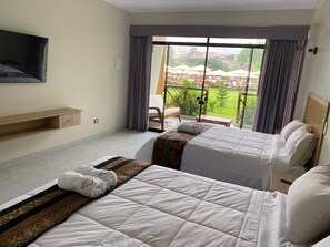 A hotel room with two beds, a TV mounted on the wall, and a balcony with a view of the city.