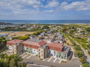 A residential area with modern houses, a parking lot, and a view of the sea. - 3 Bed in Constantine Bay (oc-t45571) (Constantine Bay)