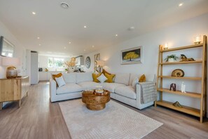 Ein modernes Wohnzimmer mit einer Eckcouch, einem Couchtisch und einem Holzregal.
