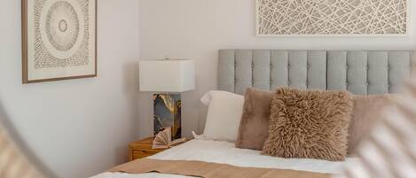 A bedroom with a bed, a nightstand, a lamp, and two wall art pieces.