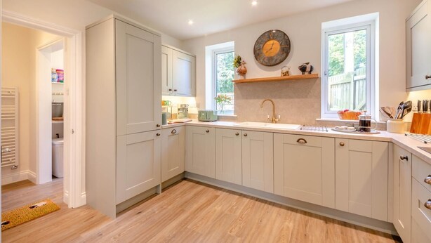 A kitchen with white cabinets, a sink, a clock, and a window. - 3 Bed in Rock (oc-r45594) (Rock)