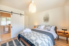 A bedroom with a bed, bedside tables, a hanging light fixture, and a door. - 3 Bed in Rock (oc-r45594) (Rock)