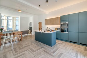 Eine moderne Küche mit einer zentralen Kochinsel, eingebauten Geräten und einem Essbereich mit Holzmöbeln.