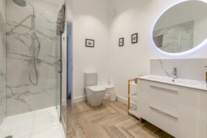 Ein modernes Badezimmer mit einer Duschkabine, einer Toilette und einem Waschtisch mit Spiegel.