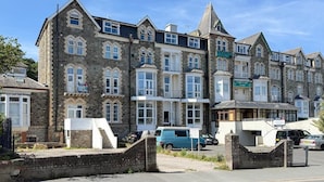 Uma fileira de edifícios altos, com espaços residenciais e comerciais, incluindo um hotel e um pub.