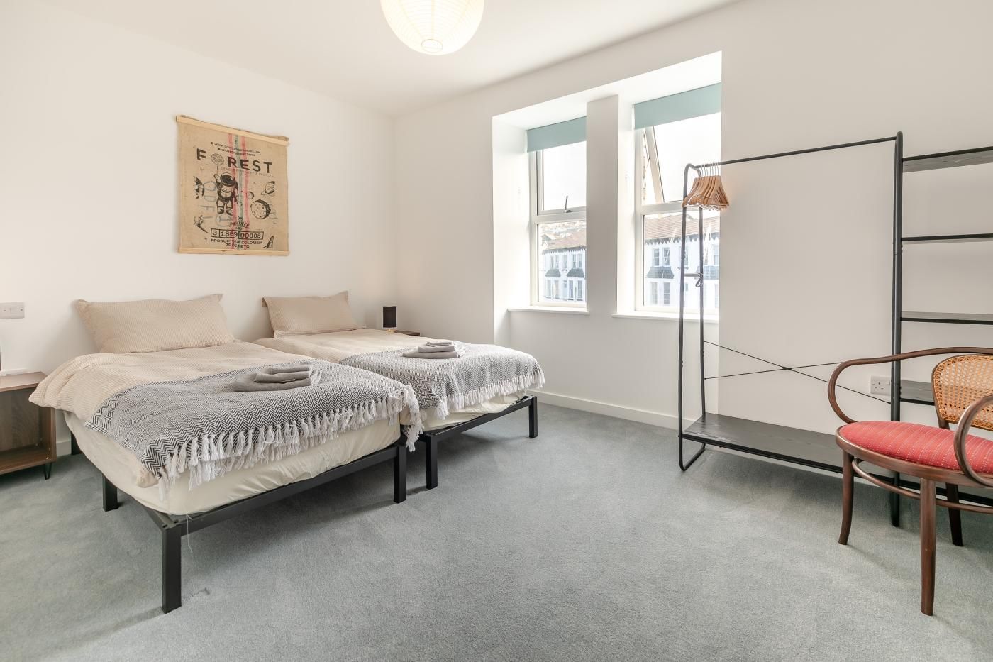 Ein Schlafzimmer mit zwei Betten, einem Sessel, einem Regal und einem Fenster.