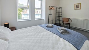 Ein Hotelzimmer mit zwei Betten, einem Sessel, einer Stehlampe und einer Heizung.