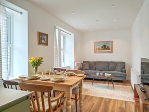 Ein Essbereich mit einem Holztisch, gedeckt für vier Personen, einer grauen Couch und einem gerahmten Bild an der Wand.