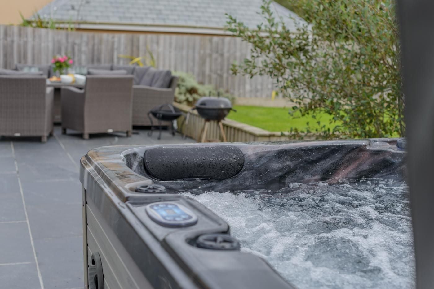 A hot tub with visible controls and a wooden fence in the background.