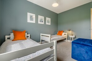 Quarto com duas beliches, uma mesinha de cabeceira com abajur e uma cadeira azul.
