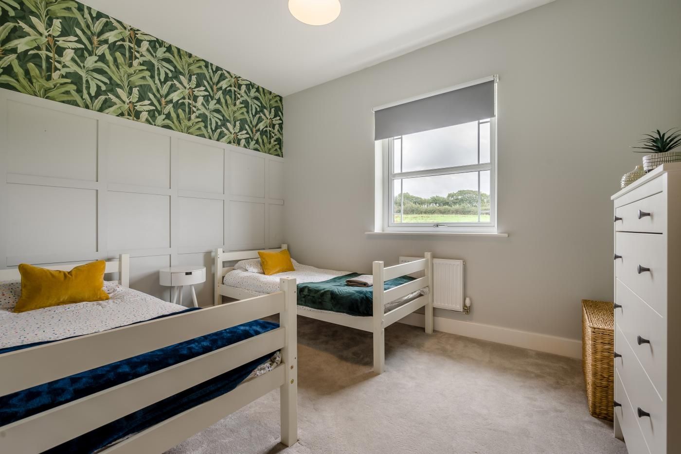 Un dormitorio con dos literas, una ventana, un radiador y un aparador.