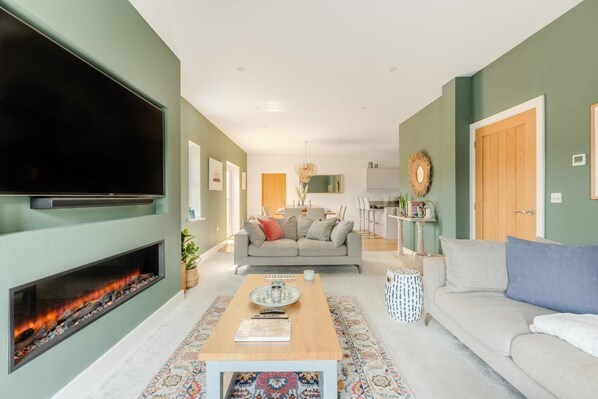 A living room with a fireplace, a sofa, a coffee table, and a television. - 4 Bed in Marhamchurch (oc-h45831) (Hobbacott)