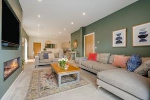 A modern living room with a fireplace, sofas, a coffee table, and artwork on the walls. - 4 Bed in Marhamchurch (oc-h45831) (Hobbacott)