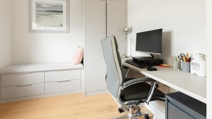 Un espai de treball minimalista amb un escriptori, una cadira, un ordinador i un quadre a la paret.