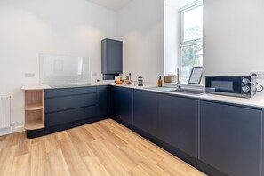 Une cuisine moderne avec des meubles de rangement aux couleurs sombres, un four encastré et une fenêtre qui laisse entrer la lumière naturelle.