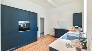 Eine moderne Küche mit eingebauten Geräten, einer zentralen Kochinsel und einem großen Fenster.