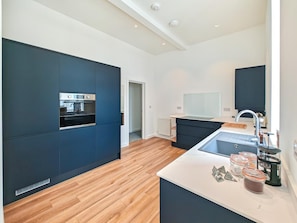 A modern kitchen with built-in appliances, a central island, and a large window. - 2 Bed in Ilfracombe (oc-b45842) (Ilfracombe)