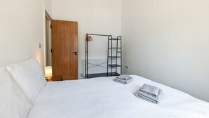 Ein Hotelzimmer mit einem Bett, einer Holztür, einem Heizkörper und einem Metalleinrichtungsregal.