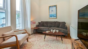Ein Wohnzimmer mit einer Couch, einem Couchtisch, einer Lampe und einem Poster an der Wand.