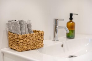 A bathroom sink with a woven basket containing towels and a soap dispenser. - 2 Bed in Ilfracombe (oc-b45842) (Ilfracombe)