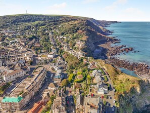 A coastal town with a mix of residential and commercial buildings, a prominent church, and a rocky coastline. - 2 Bed in Ilfracombe (oc-b45842) (Ilfracombe)