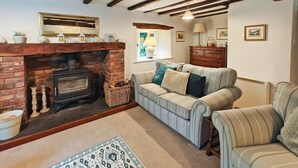 Ein gemütliches Wohnzimmer mit Kamin, gestreifter Couch und Holzboden.