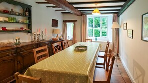Ein Essbereich mit einem Tisch, der mit einer Tischdecke mit Punkten bedeckt ist, Holzsesseln und einer Kristallleuchtre.